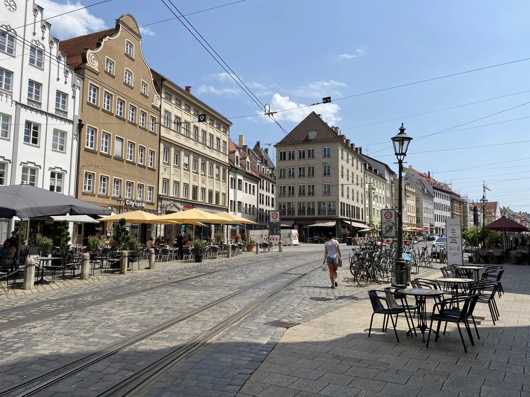 Maximilianstraße in Augsburg mit Cafés und historischen Fassaden bei Sonne