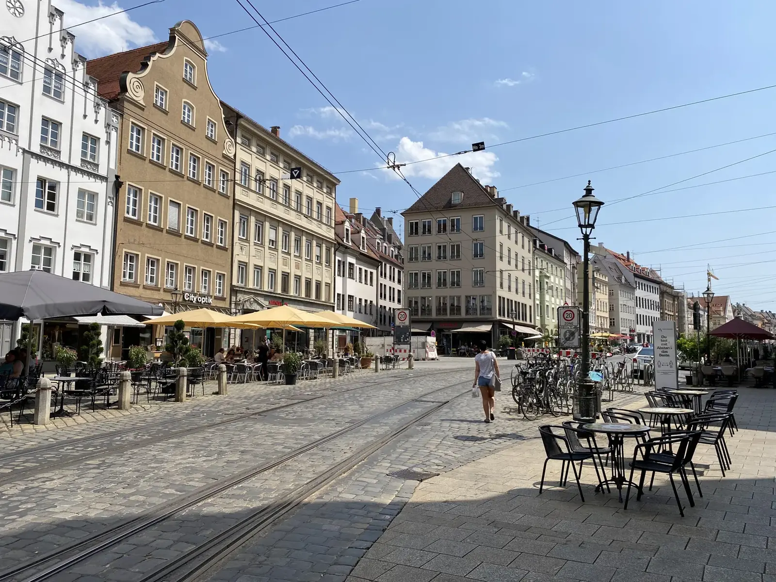 Maximilianstraße in Augsburg mit Cafés und historischen Fassaden bei Sonne