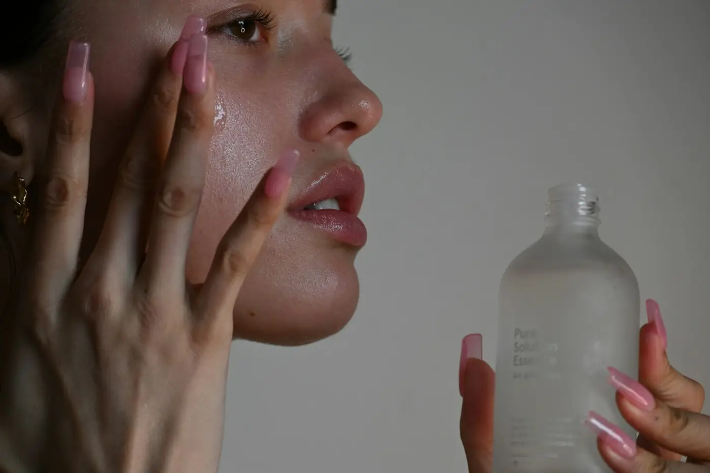 Frau trägt Pflege auf, in der Hand eine Glasflasche