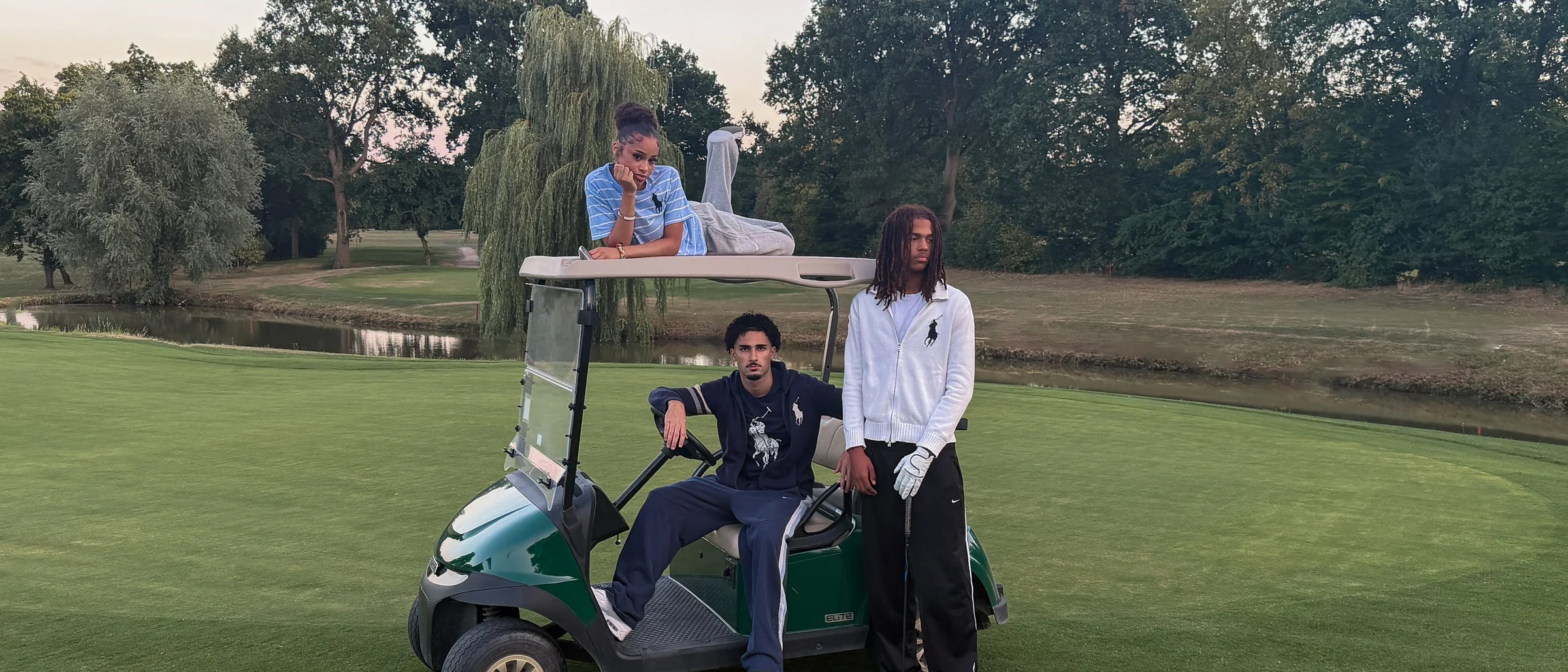 Sportpacks-Kampagne: drei Personen in Vintage-Sportswear an einem Golfcart auf dem Golfplatz