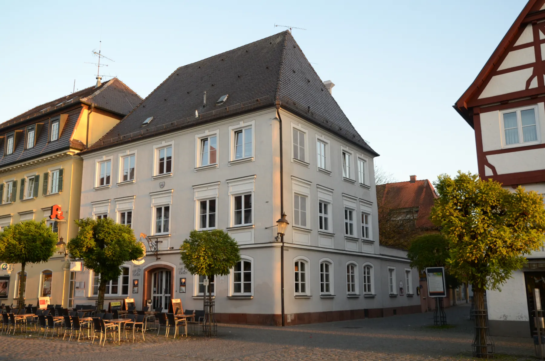 Haus am Marktplatz in Günzburg in der Abendsonne, davor Tische eines Cafés