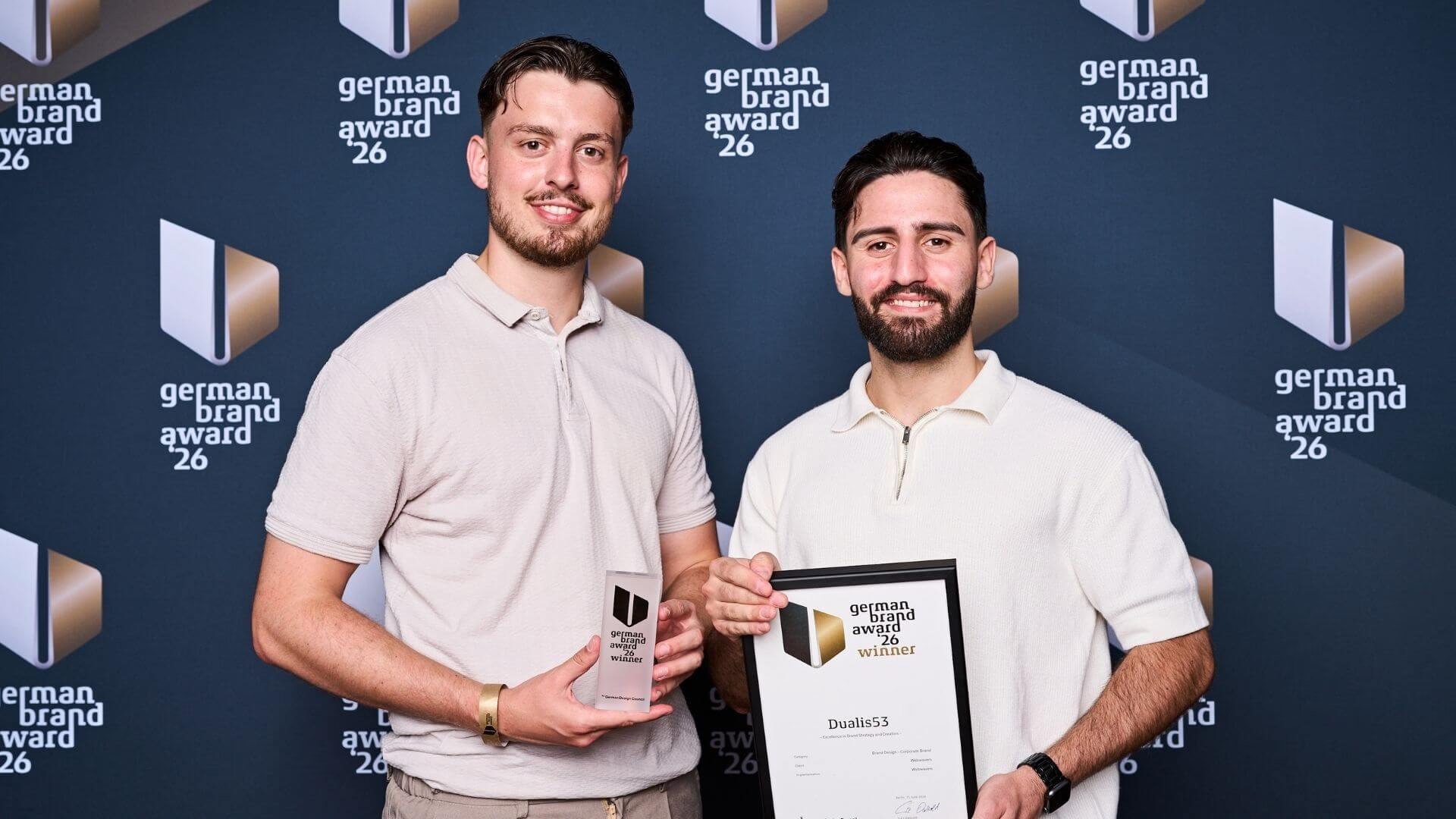 Zwei Projektbeteiligte mit Dualis53-Urkunde und Trophäe beim German Brand Award 2026